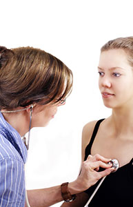 Female health care professional uses stethoscope to listen to a young woman's heartbeat