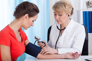 Young woman patient has her blood pressure checked by a woman medical professional