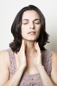 Young woman with eyes closed holds her hands to her neck as if in pain