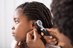 Medical practitioners uses otoscope to check girl's ear