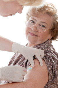 Older woman getting a shot from a medical professional